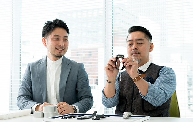 Photo of Monjugawa and Kishino staring at the watch