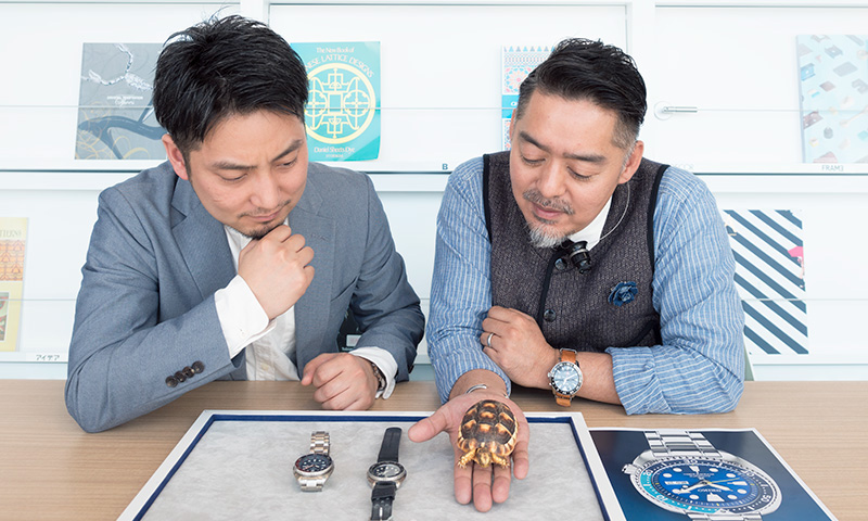 Photo of Monjugawa and Kishino comparing the Turtle watch with a live turtle