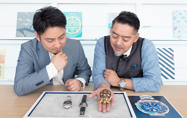 Photo of Monjugawa and Kishino comparing the Turtle watch with a live turtle