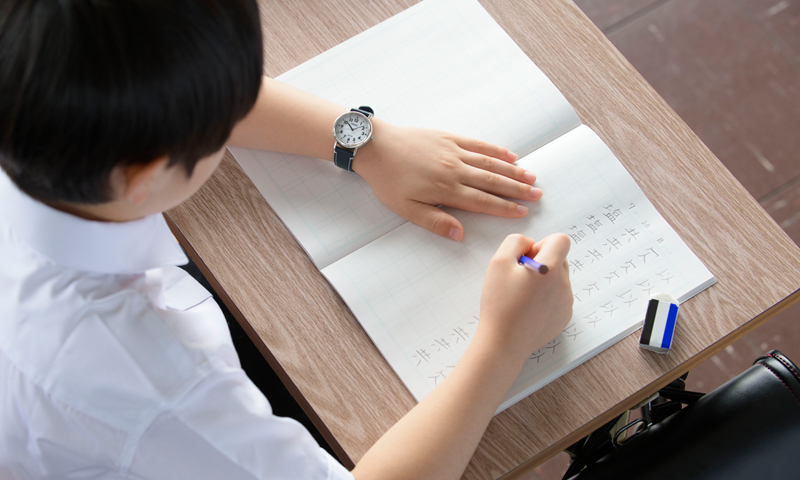 スクールタイムをつけて、漢字の練習をする小学生の写真
