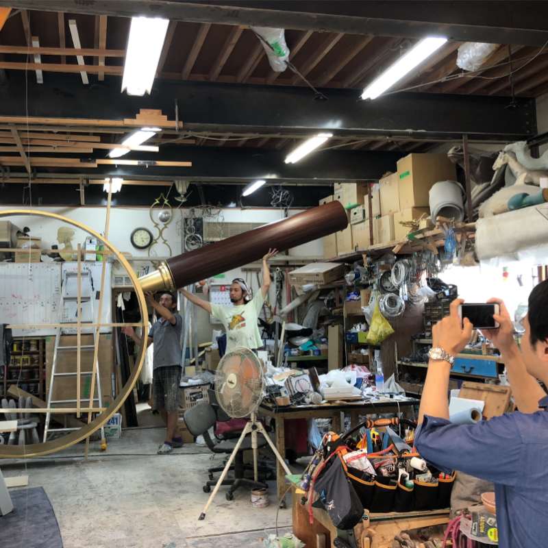 Photo of a huge magnifying glass in the middle of production. The diameter of the lens part is larger than the staff.