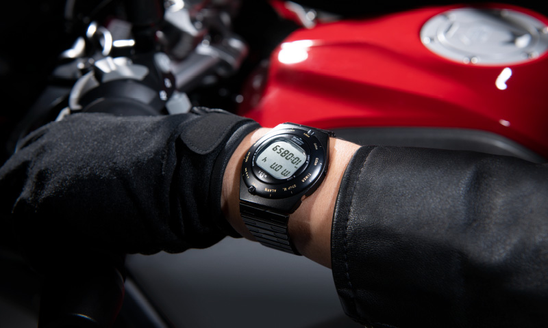 Photo of Speedmaster on the left hand gripping the handlebar of a motorcycle