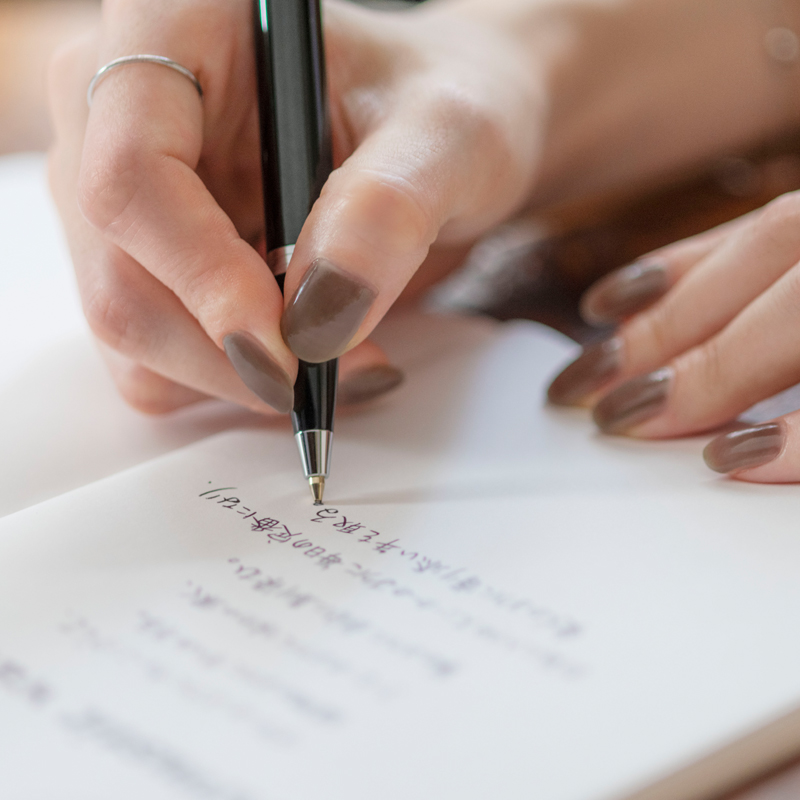 Photo of a hand writing a poem in a notebook