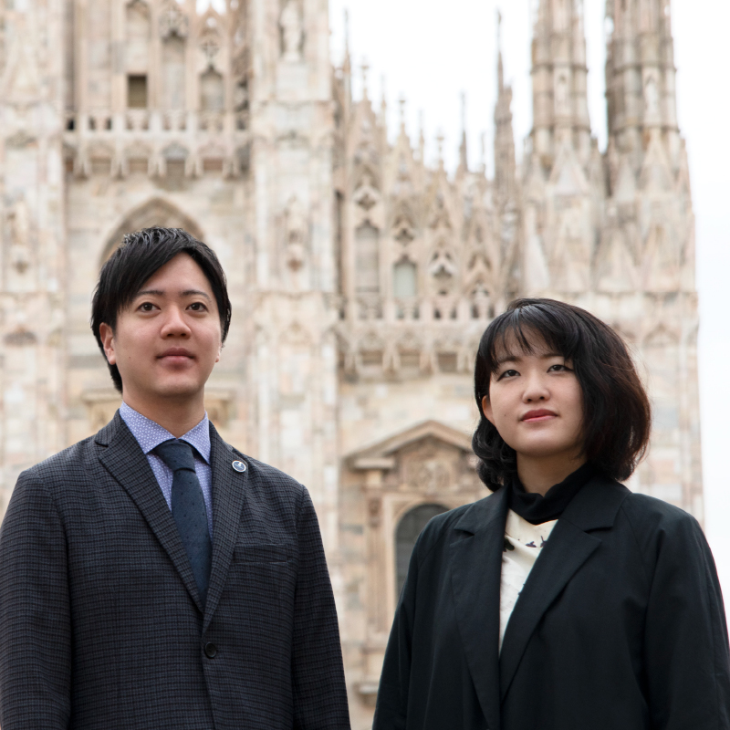 Yoshida and Koriyama standing in the Piaza del Duomo in front of the Milan Cathedral